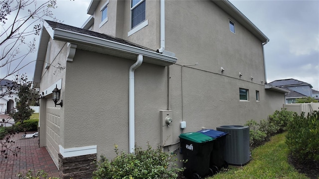 view of side of home featuring central air condition unit and stucco siding