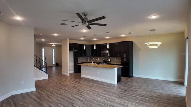 kitchen with visible vents, light wood-type flooring, appliances with stainless steel finishes, open floor plan, and backsplash