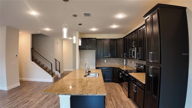 kitchen featuring visible vents, a sink, tasteful backsplash, appliances with stainless steel finishes, and light wood finished floors