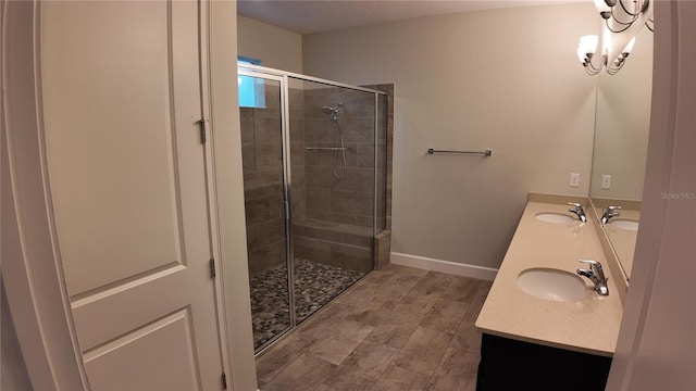 full bathroom with double vanity, baseboards, a stall shower, and a sink