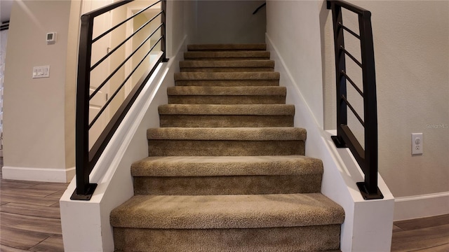 staircase with wood finished floors and baseboards