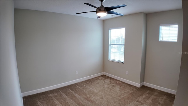 carpeted empty room with ceiling fan and baseboards