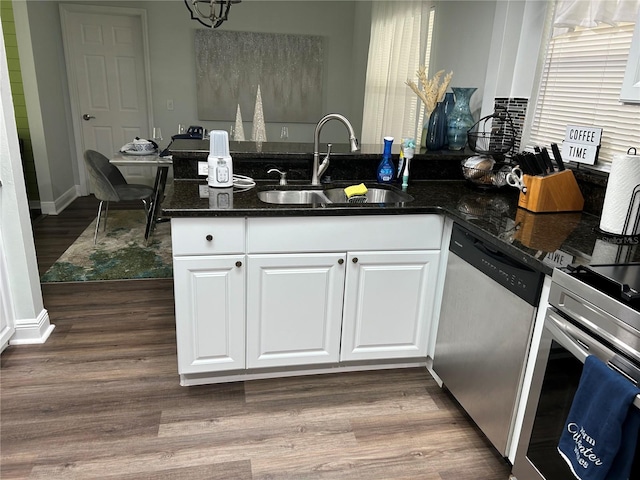 kitchen featuring dishwasher, sink, dark stone counters, wood-type flooring, and white cabinets