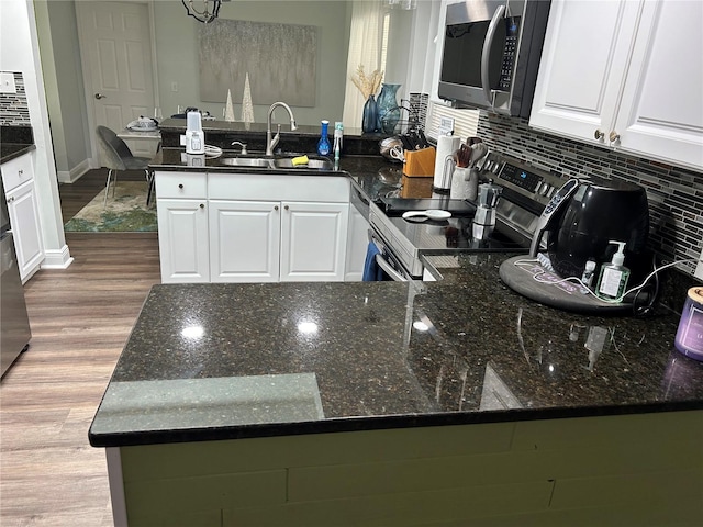 kitchen featuring white cabinets, stainless steel appliances, dark stone countertops, and sink