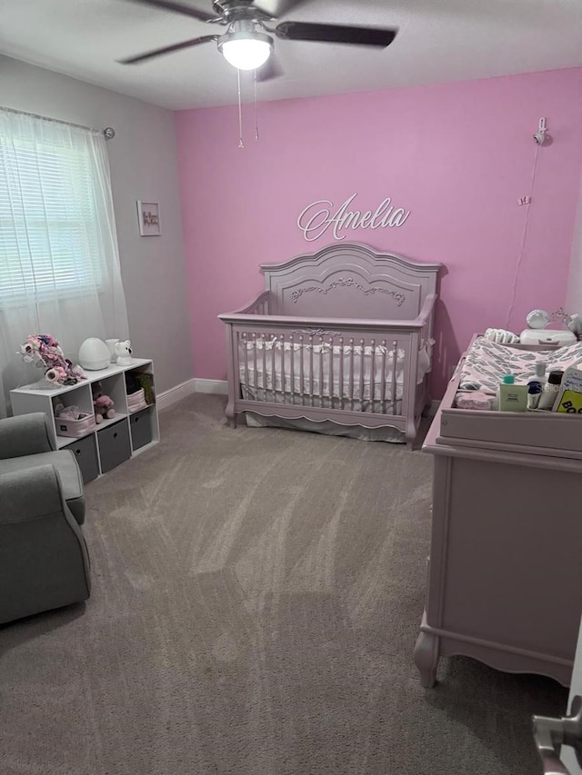 carpeted bedroom with a crib and ceiling fan