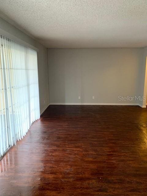 unfurnished room featuring a textured ceiling and dark hardwood / wood-style floors