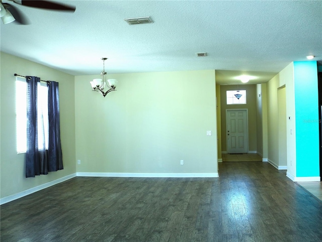 unfurnished room with a textured ceiling, ceiling fan with notable chandelier, and dark hardwood / wood-style floors