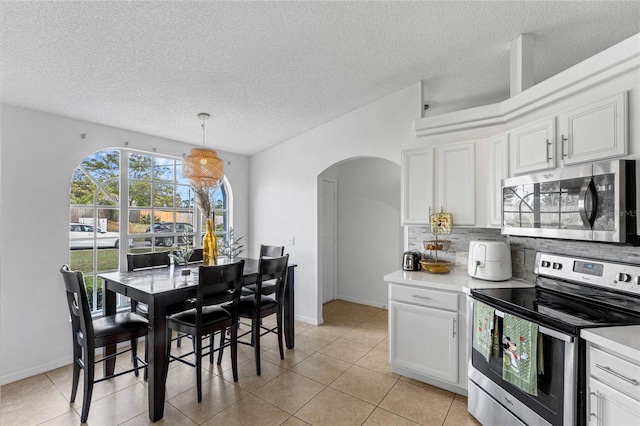 kitchen with pendant lighting, white cabinets, light tile patterned floors, a textured ceiling, and stainless steel appliances