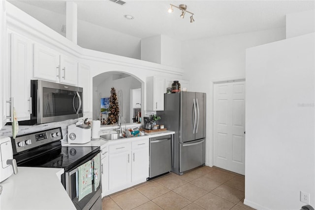 kitchen with sink, white cabinets, stainless steel appliances, and high vaulted ceiling