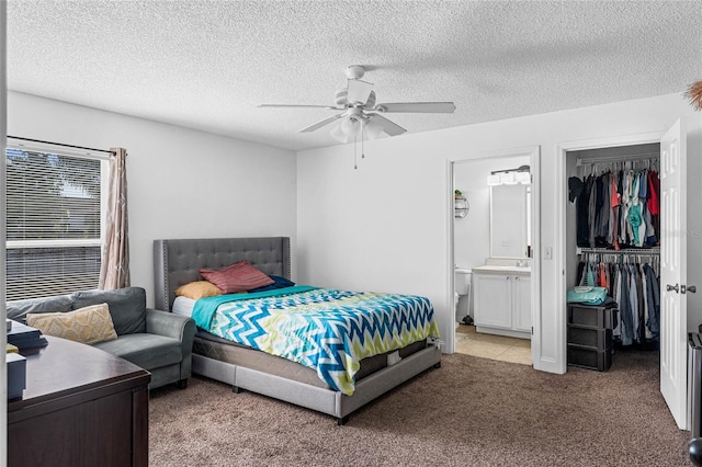 carpeted bedroom featuring a textured ceiling, ensuite bathroom, and ceiling fan