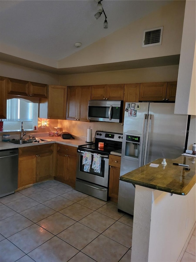 566/568 Imperial Pl, Kissimmee, FL 34758 - kitchen with appliances with stainless steel finishes, a sink, lofted ceiling, brown cabinets, and light tile patterned flooring