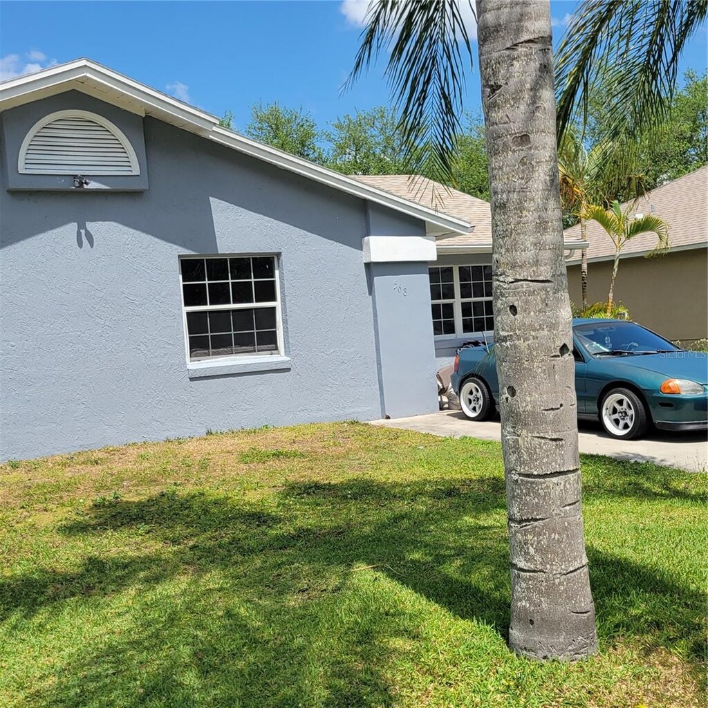 exterior space featuring stucco siding and a lawn