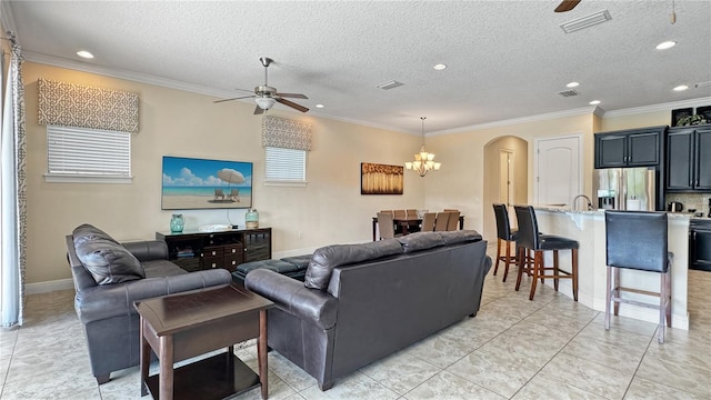 living room with a textured ceiling, ceiling fan with notable chandelier, and crown molding