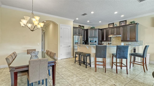 kitchen featuring decorative backsplash, an inviting chandelier, light stone counters, and crown molding