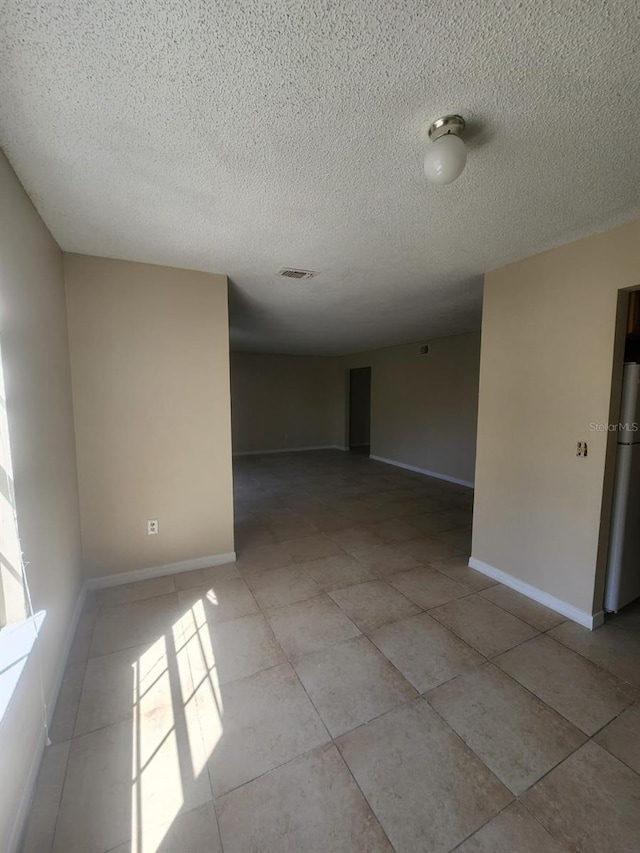 spare room featuring light tile patterned flooring and a textured ceiling