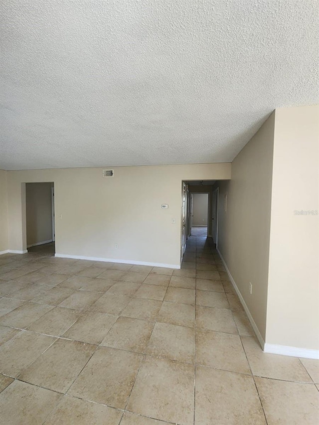 tiled spare room with a textured ceiling