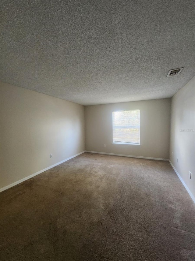 carpeted spare room with a textured ceiling