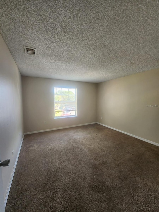 empty room featuring dark carpet and a textured ceiling