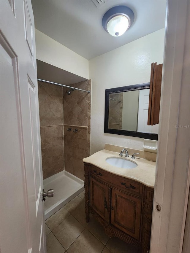 bathroom with tile patterned flooring, vanity, and tiled shower