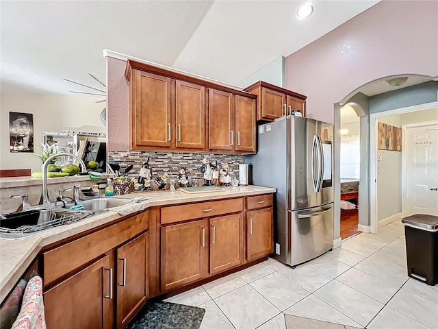 kitchen featuring backsplash, stainless steel fridge, sink, and light tile patterned flooring