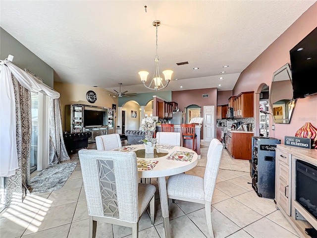 tiled dining area featuring a textured ceiling and ceiling fan with notable chandelier