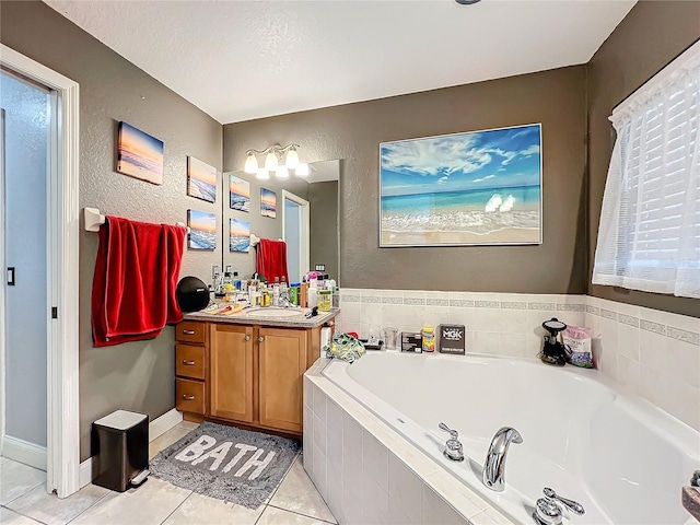 bathroom featuring tile patterned flooring, a textured ceiling, vanity, and tiled bath