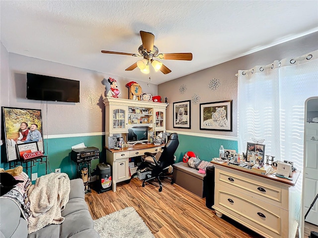 home office featuring ceiling fan, light hardwood / wood-style floors, and a textured ceiling