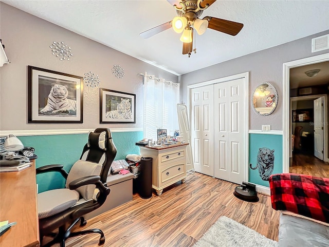 home office with light hardwood / wood-style flooring and ceiling fan