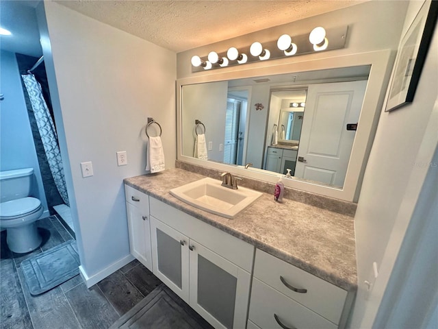 bathroom featuring a shower with shower curtain, vanity, a textured ceiling, hardwood / wood-style floors, and toilet