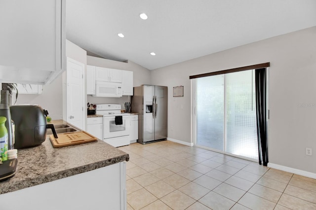 kitchen with white cabinets, light tile patterned flooring, white appliances, and vaulted ceiling