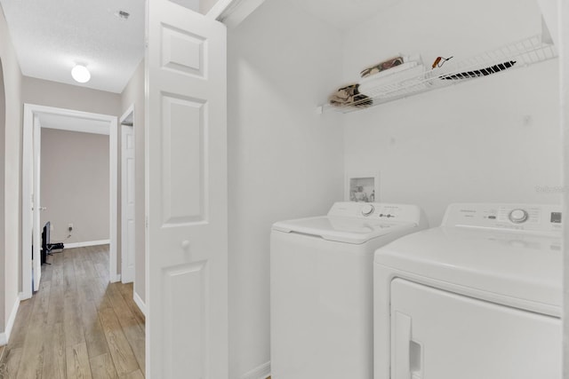 clothes washing area featuring independent washer and dryer, a textured ceiling, and light hardwood / wood-style flooring