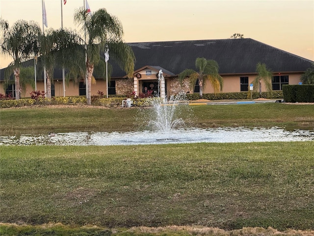 view of home's community with a water view and a lawn