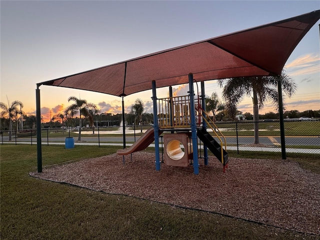 playground at dusk featuring a lawn