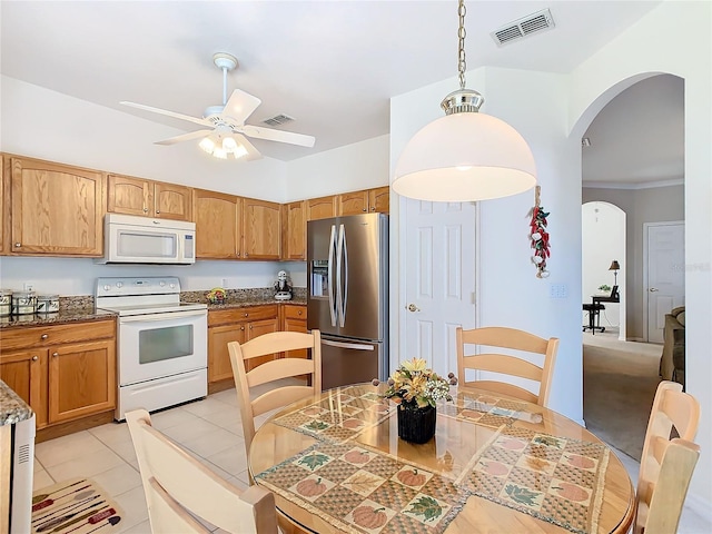 kitchen featuring dark stone counters, white appliances, ceiling fan, light tile patterned floors, and decorative light fixtures