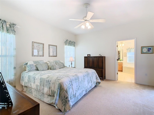 bedroom featuring ceiling fan, ensuite bath, light carpet, and multiple windows