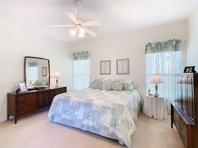 bedroom featuring multiple windows, ceiling fan, and light carpet