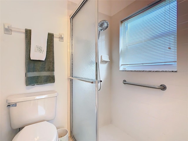 bathroom featuring toilet and a shower with door