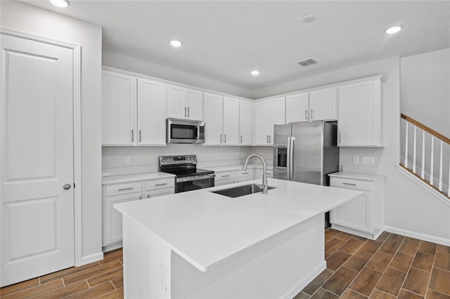 kitchen featuring white cabinets, a kitchen island with sink, sink, and appliances with stainless steel finishes