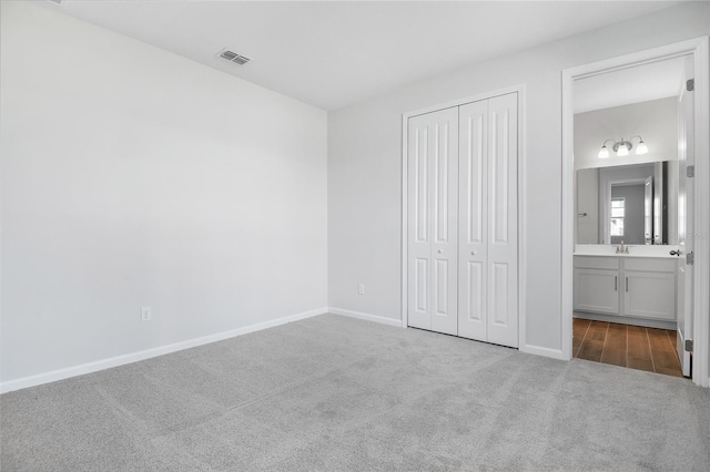 unfurnished bedroom featuring carpet flooring, ensuite bath, and a closet