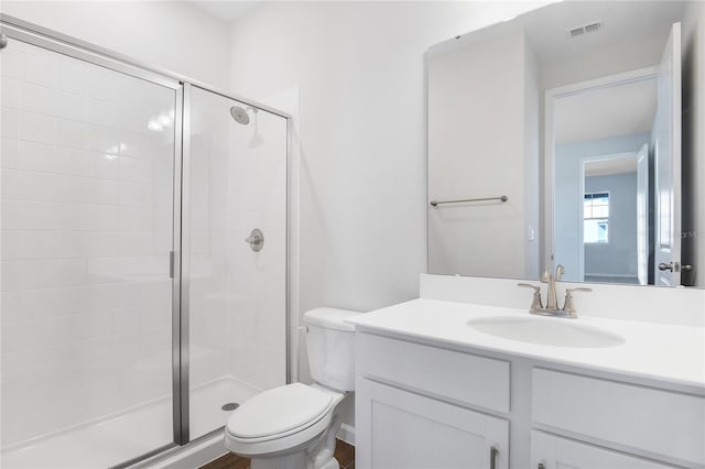 bathroom featuring vanity, a shower with shower door, and toilet