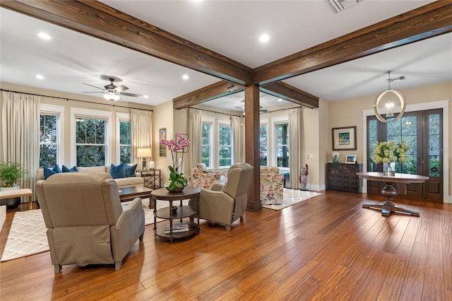 living room with beamed ceiling, ceiling fan with notable chandelier, and light hardwood / wood-style flooring