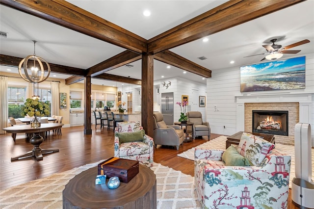 living room featuring beam ceiling, light wood-type flooring, a fireplace, and wooden walls