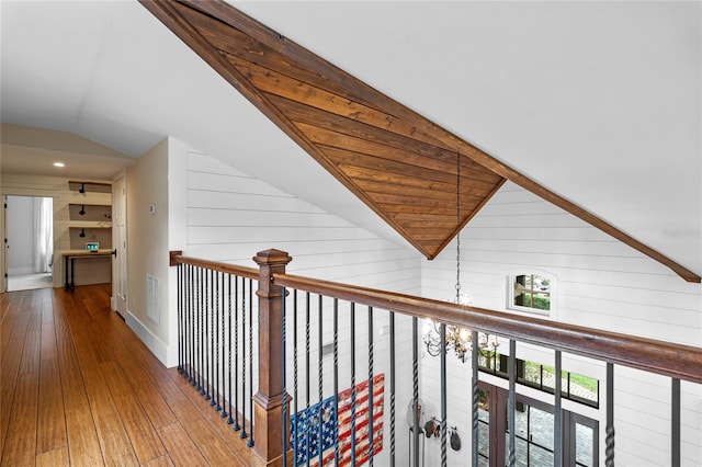 corridor with wooden walls, hardwood / wood-style floors, and lofted ceiling