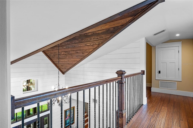 corridor featuring a notable chandelier, lofted ceiling, and wood-type flooring