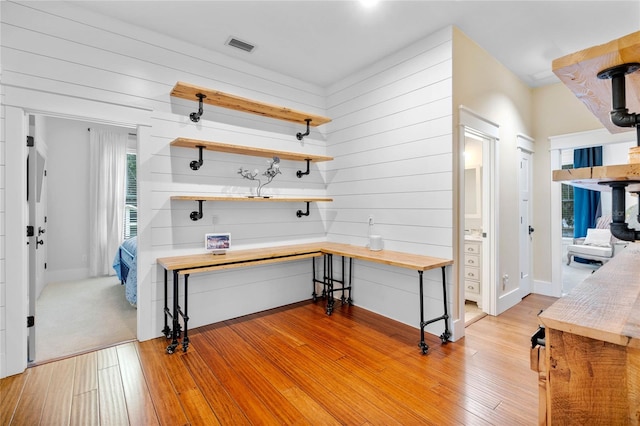 interior space with butcher block countertops, light hardwood / wood-style floors, and wooden walls