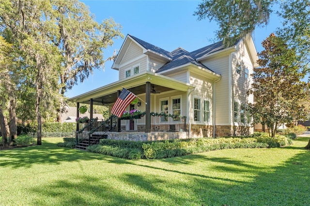 view of front of home with a front yard, ceiling fan, and covered porch