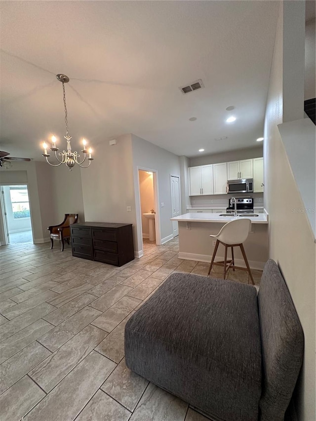 interior space featuring a kitchen bar, decorative light fixtures, kitchen peninsula, stainless steel appliances, and white cabinets