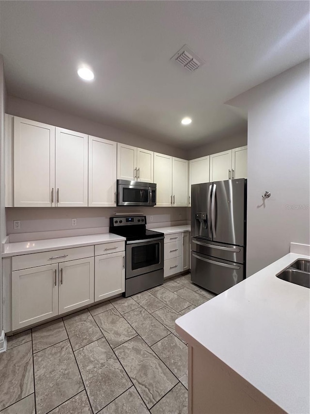 kitchen with appliances with stainless steel finishes, sink, and white cabinets