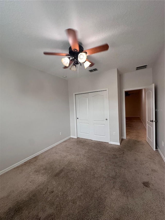 unfurnished bedroom with a textured ceiling, a closet, ceiling fan, and carpet flooring