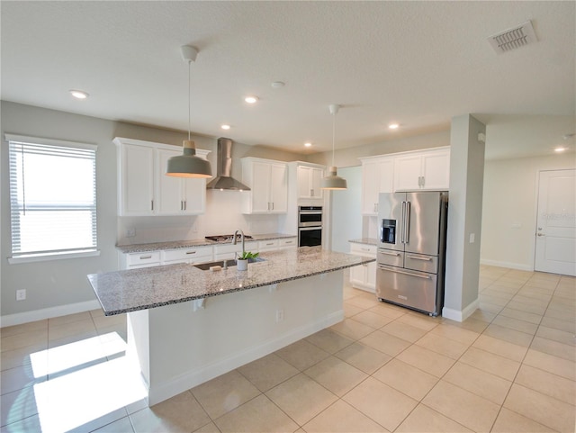 kitchen with white cabinetry, light stone countertops, stainless steel appliances, and wall chimney range hood